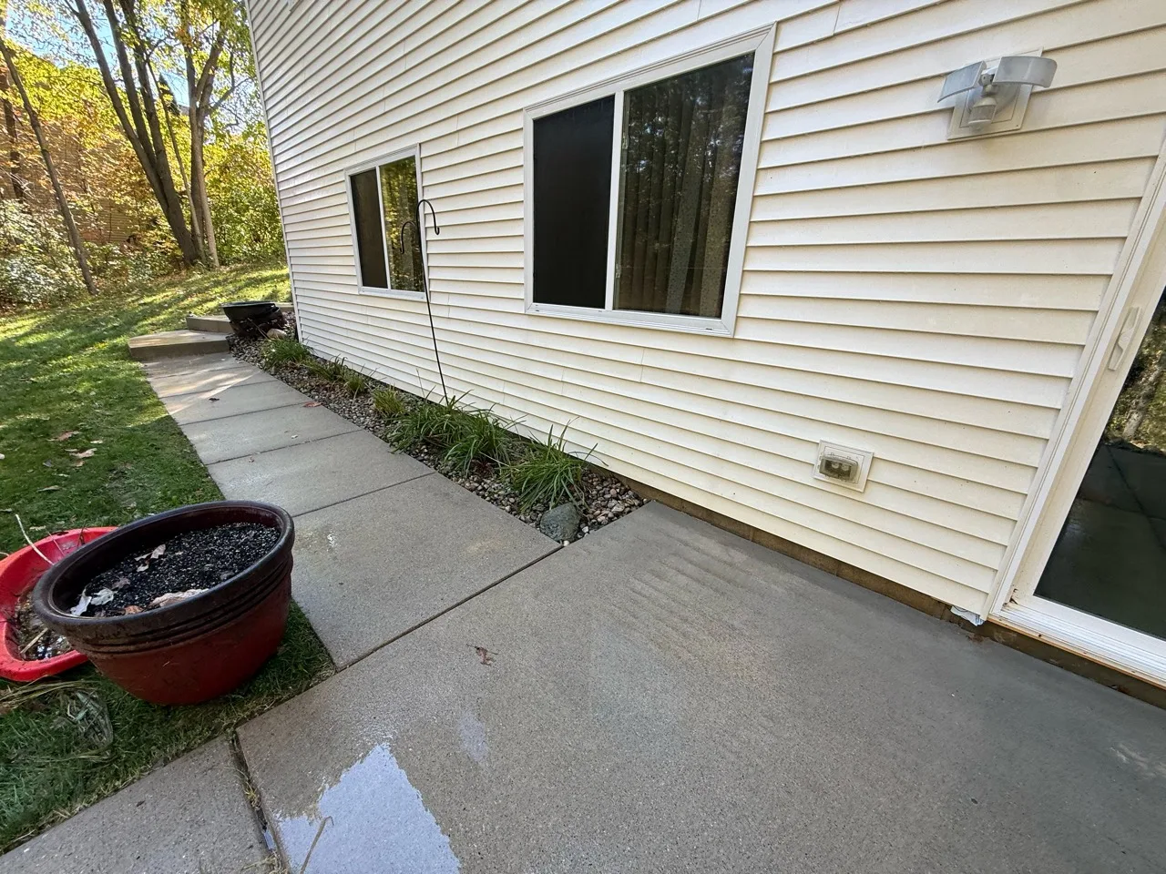 Concrete walkway beside light vinyl siding and sliding glass doors