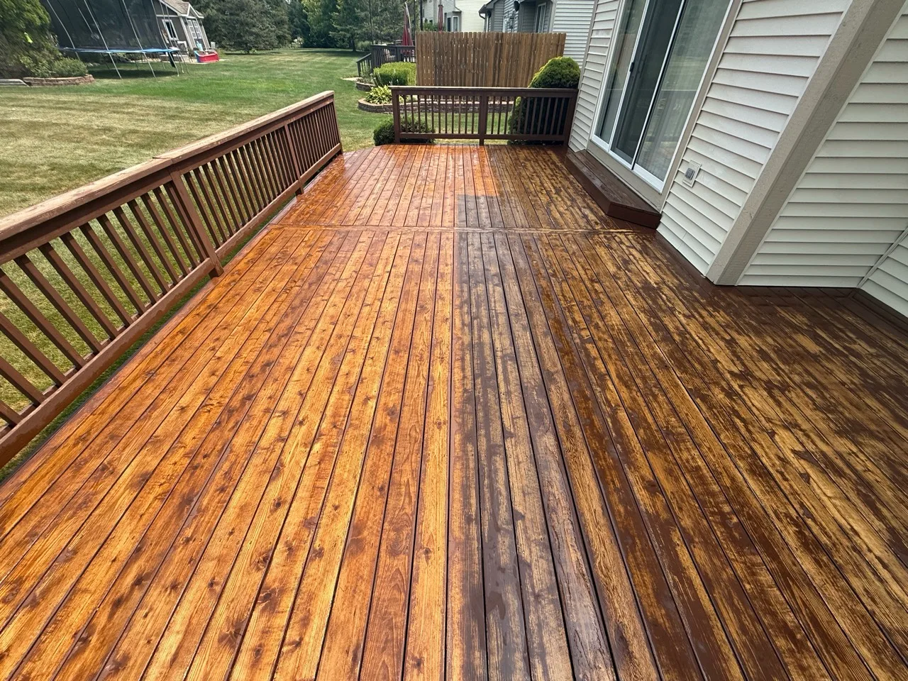 Wet wood deck showing worn finish during a cleaning or preparation stage