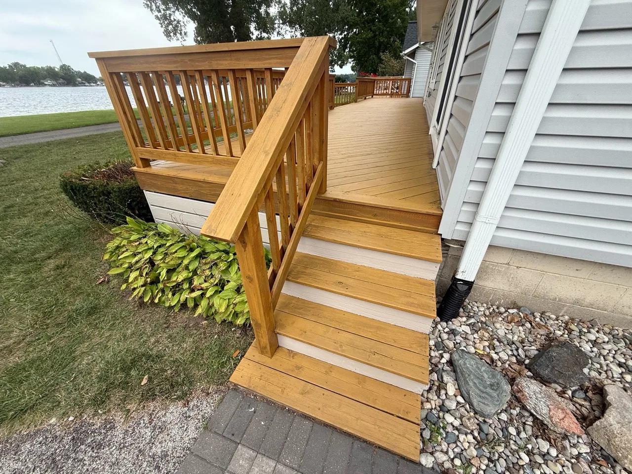 Golden-toned wood deck steps and railing beside a house