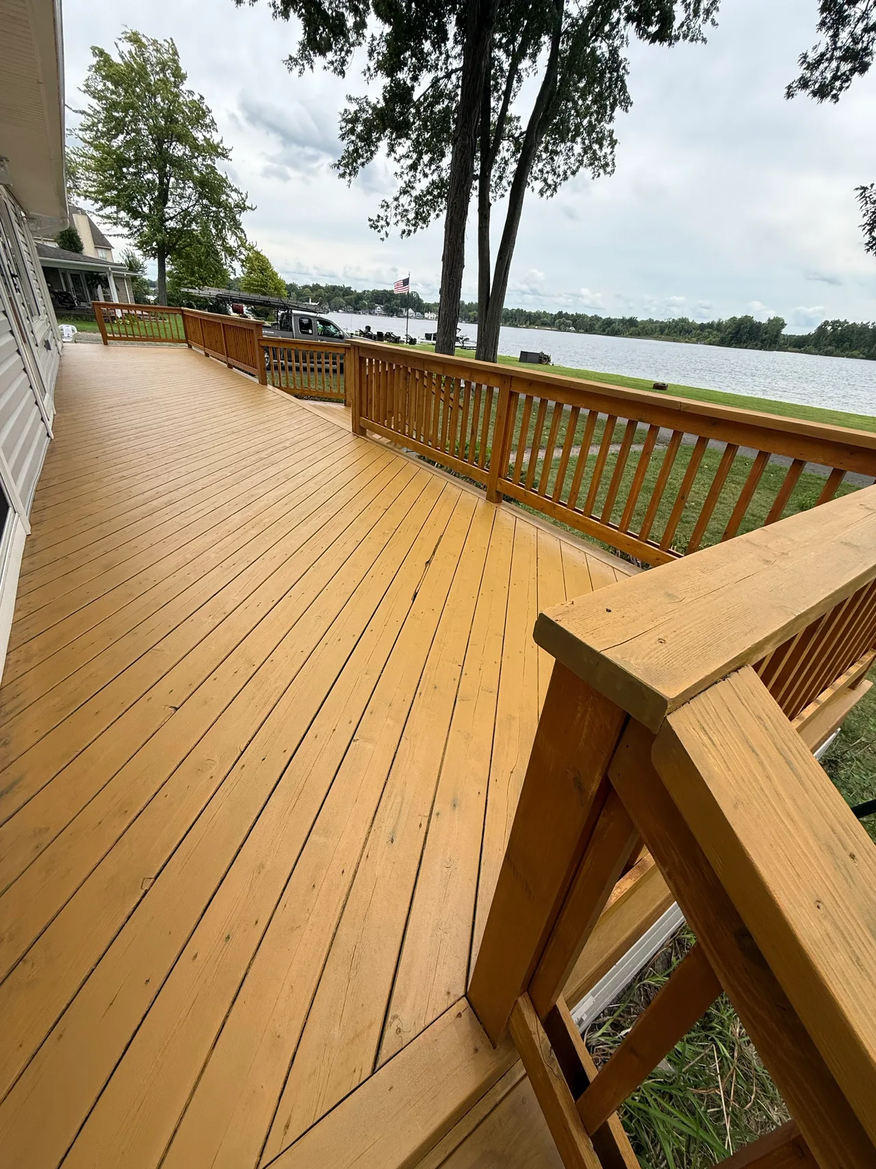 Golden-toned wood deck and railing overlooking a lake