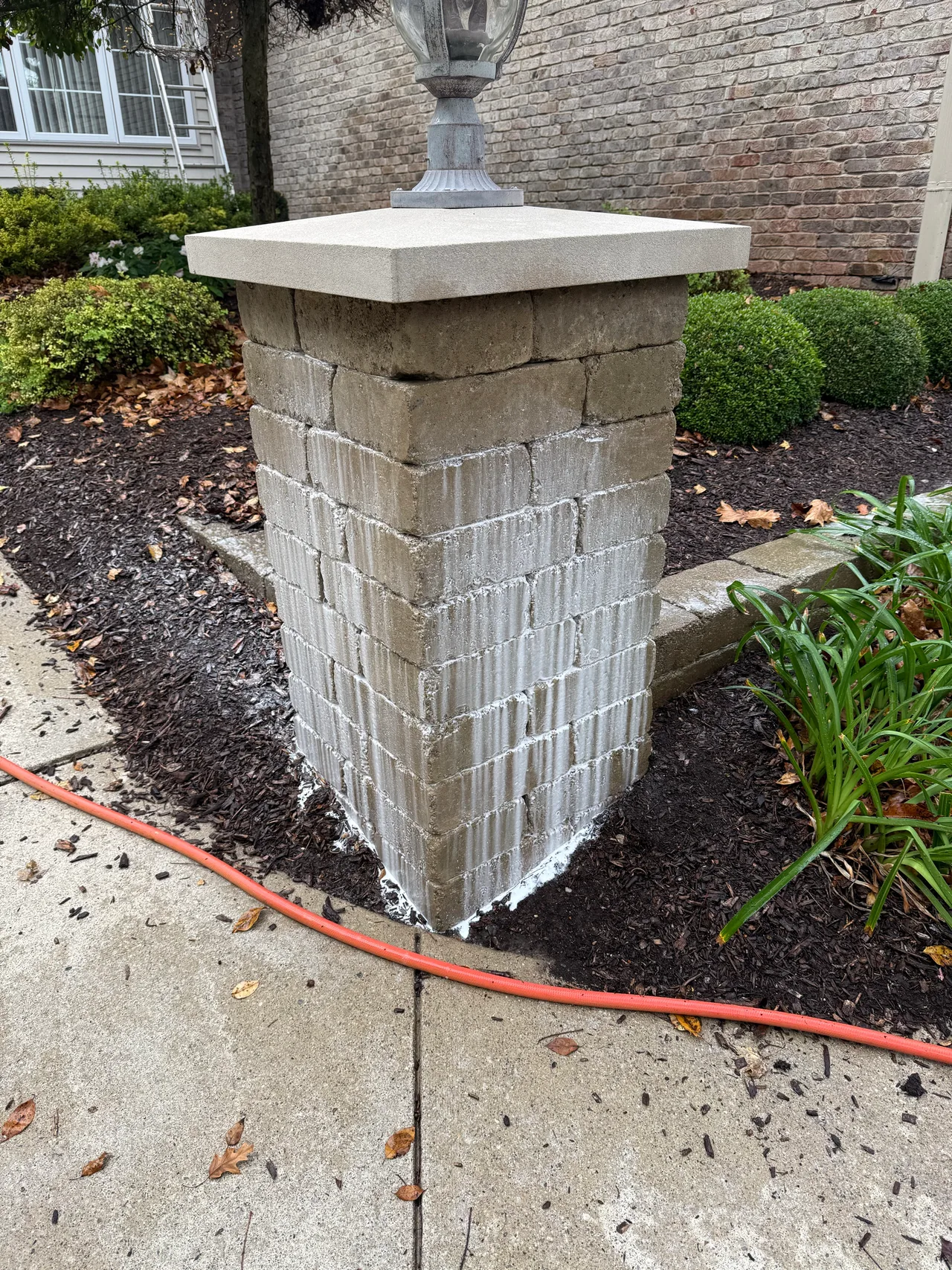 Masonry light pillar with cleaning foam running down its surface