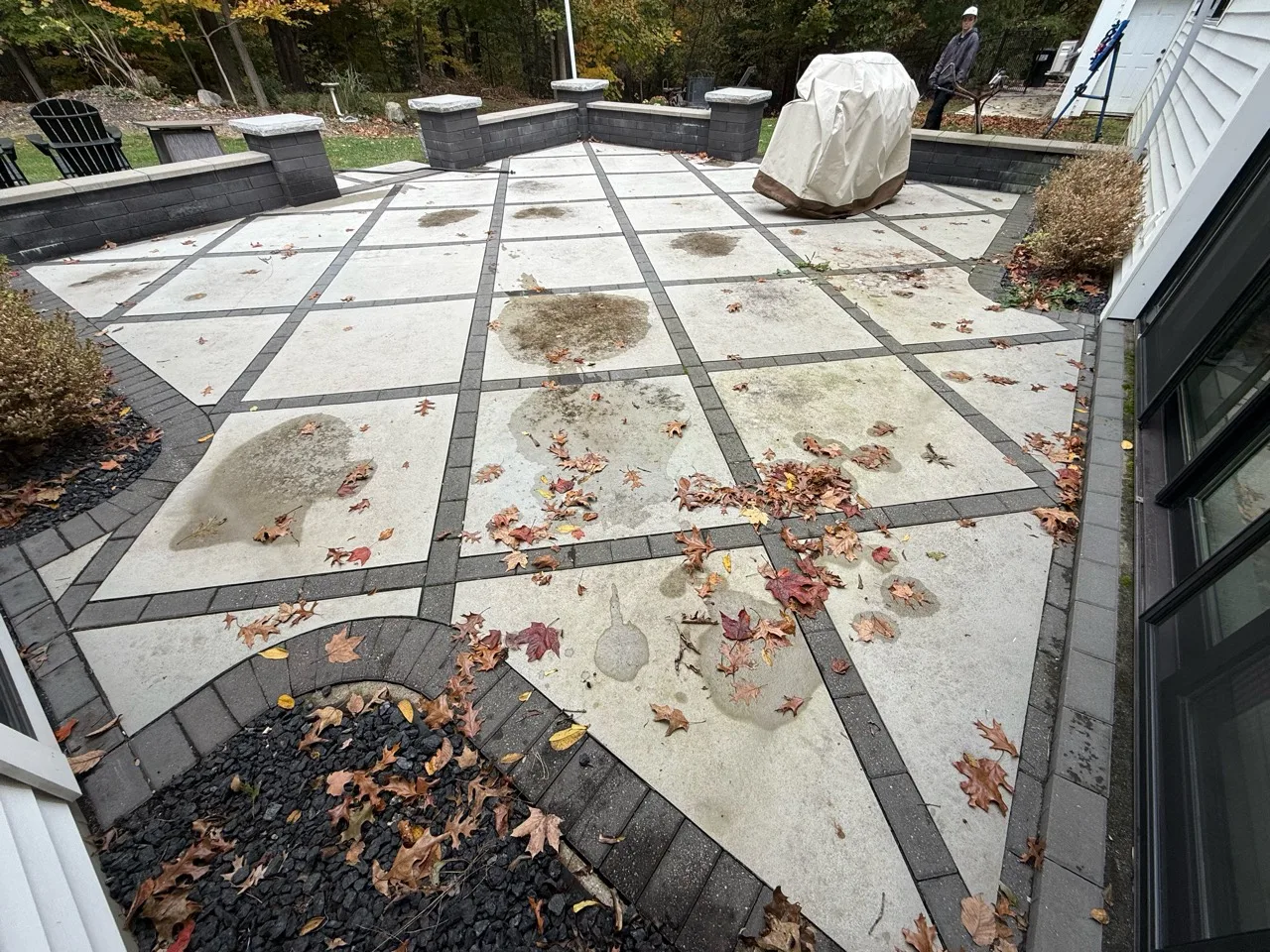 Patterned patio with leaves and visible dark surface buildup before cleaning
