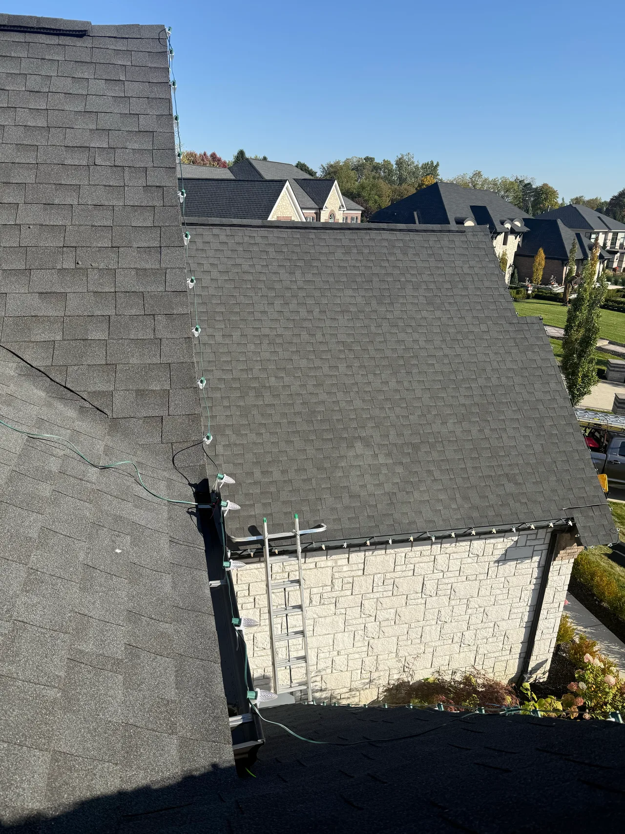 Daytime view of holiday light strands following multiple roof edges