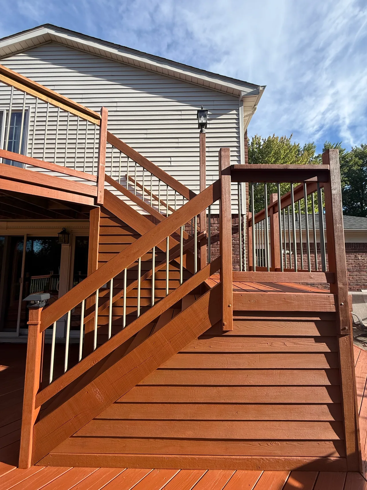 Close view of wood deck stairs and rail posts with a warm orange-brown stain